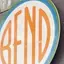 The emblem on Storefront sign: the disc in orange capitals inside a teal ring, The Bend Store, January 6, 2019.