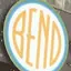 The emblem on The storefront sign, behind a group photograph in snowfall, The Bend Store, February 25, 2019.