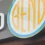 The emblem on The storefront sign, and a blue tee with a white disc on a mannequin, The Bend Store, August 2, 2024.