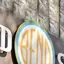 The emblem on The storefront sign, and discs hanging in the window, The Bend Store, May 11, 2026.