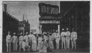 A group posed beside the Bend Park Company’s Seattle booth, beneath a large lettered BEND sign.