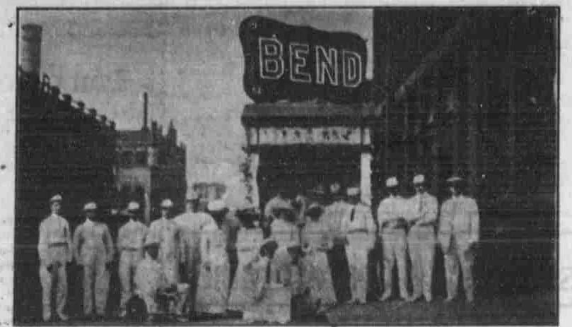 A group posed beside the Bend Park Company’s Seattle booth, beneath a large lettered BEND sign.