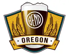 A pint glass topped by the Three Sisters, with a tilted white Bend emblem, barley and an Oregon banner.