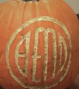 A pumpkin with a circular BEND emblem carved into its rind, the letters pale against the orange.