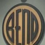 A large wooden disc on a wall, the word BEND cut into its tan face inside a dark ring.