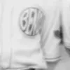 A circular emblem stitched to the left chest of a white baseball jersey, the word BEND filling it.