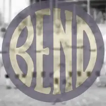 A gold disc filled edge to edge by the word BEND in broad letters, laid over a faded photograph of baseball players.