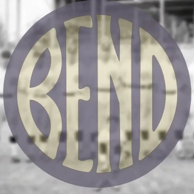 A gold disc filled edge to edge by the word BEND in broad letters, laid over a faded photograph of baseball players.