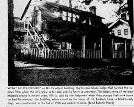A newspaper photograph of a large wooden lodge behind a picket fence, with a covered porch and an exterior stair, captioned “What of its future?”