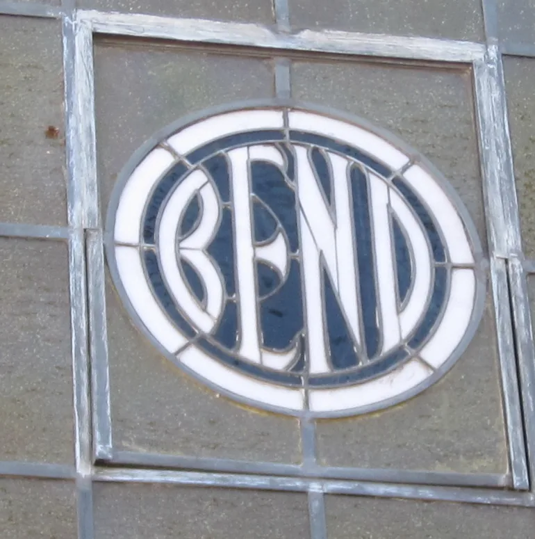 White BEND letters within a circular border, set in a stained-glass transom and its weathered frame.
