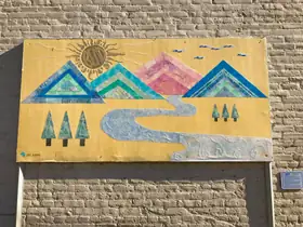 Roadman’s mountain-and-river artwork mounted on a brick wall, photographed in 2017.