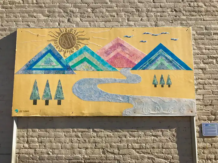 Roadman’s mountain-and-river artwork mounted on a brick wall, photographed in 2017.