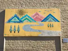 Roadman’s mountain-and-river artwork mounted on a brick wall, photographed in 2017.