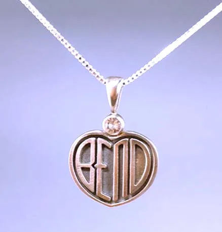 A heart-shaped silver Bend pendant with narrow letters, an arched n and a sunstone above it.