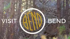 A gold Bend emblem within a white circle, flanked by VISIT and BEND over a forest photograph.